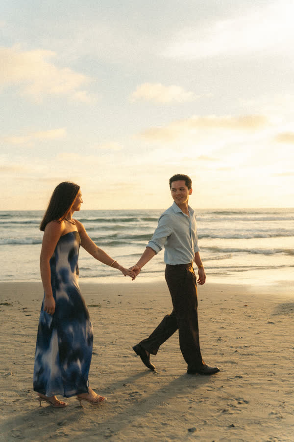 Dylan and Jessica walking hand in hand along the beach at golden hour
